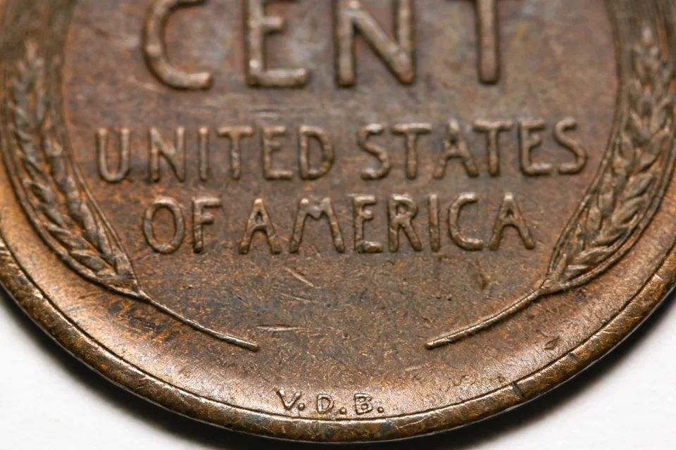 Macro of the V.D.B. designer initials at the base of a 1909 wheat penny reverse — the mark that identifies the $800+ 1909-S VDB key date